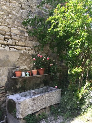 A stone wall with a shelf holding terracotta pots and a stone planter. - Charming Studio Le Mas de Kitty, Shared Garden and Pool (Saint-Rémy-de-Provence)