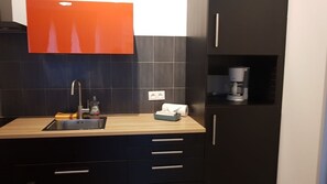 A modern kitchen with a sink, countertop, and dark cabinetry. - Charming Studio Le Mas de Kitty, Shared Garden and Pool (Saint-Rémy-de-Provence)