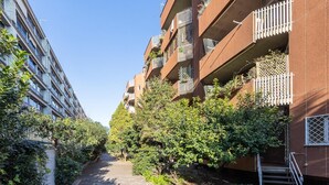 Een smal pad begrensd door meerverdiepingsgebouwen met balkons, waarvan sommige beplant zijn.