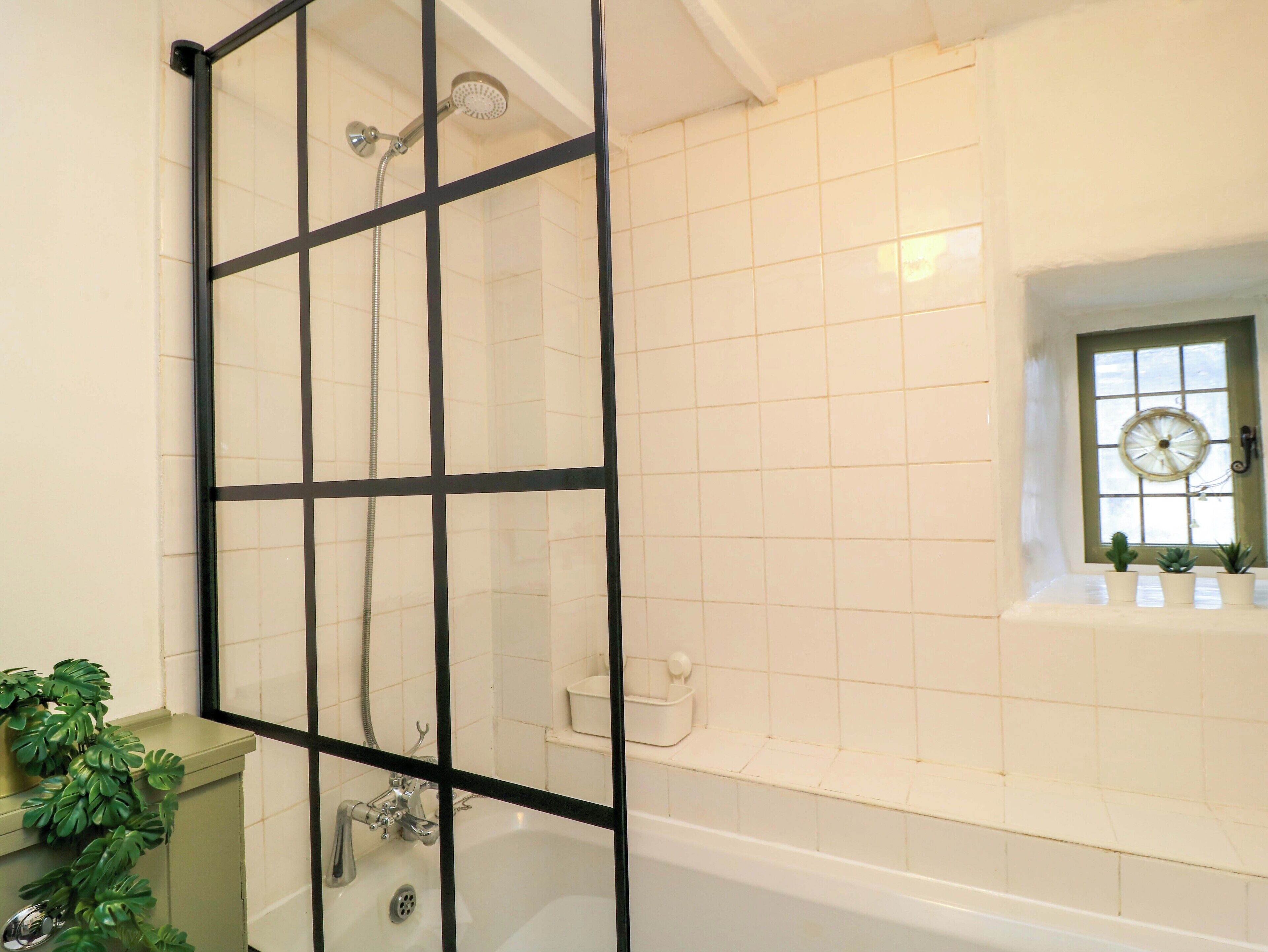 A bathroom with a shower enclosure, a bathtub, and a window with a view.