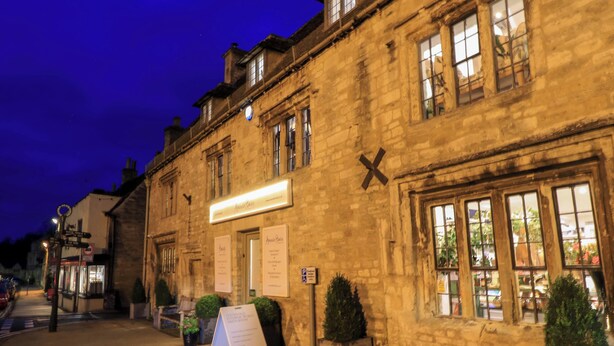 A stone building with a signboard, a small signboard, and a potted plant. - Burford Apple (Burford)
