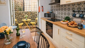 A compact kitchen with a dining area, featuring a stone wall, a microwave, and a variety of kitchenware. - Burford Apple (Burford)