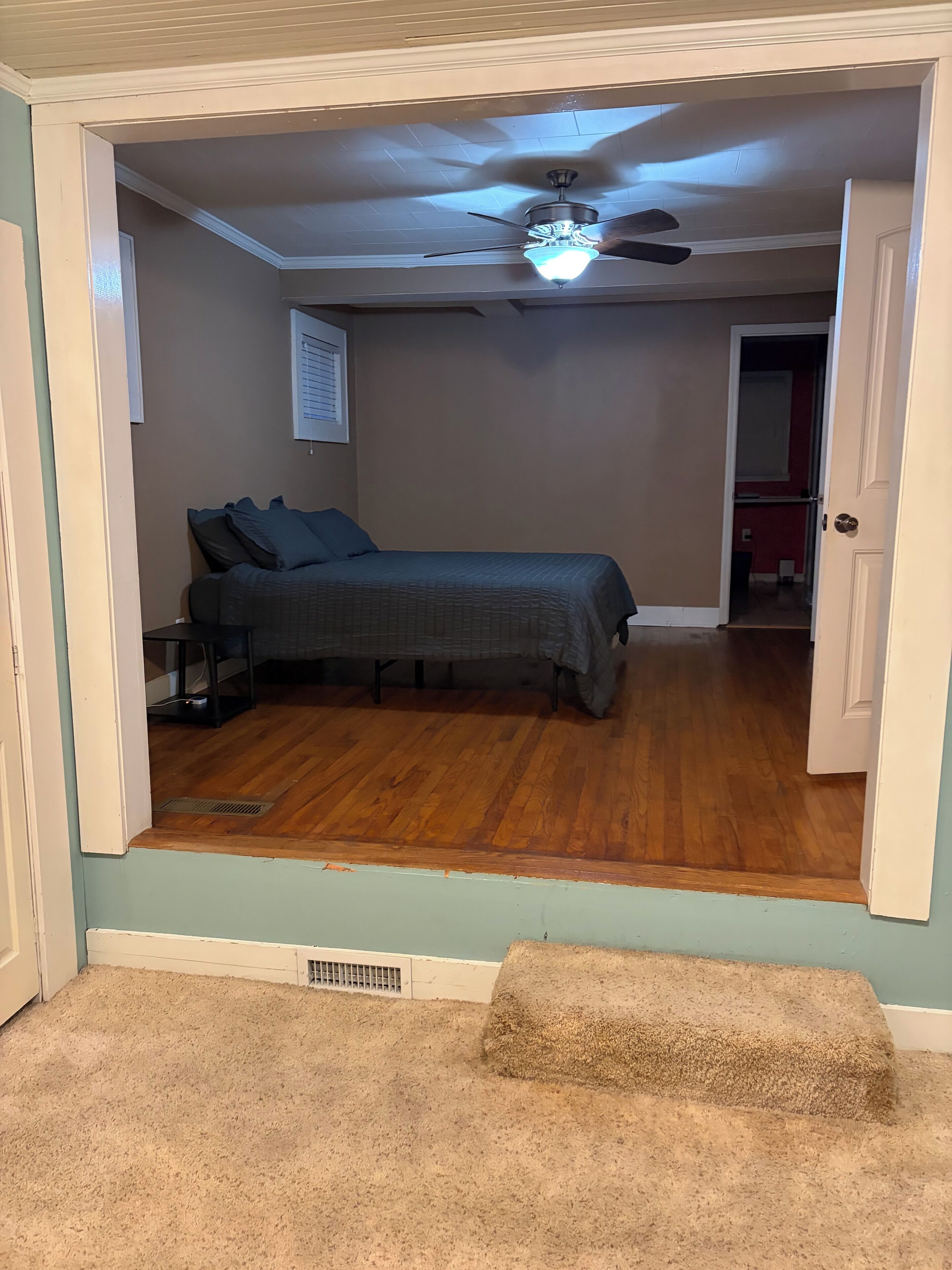 A bedroom with a bed, a ceiling fan, and a window with blinds.