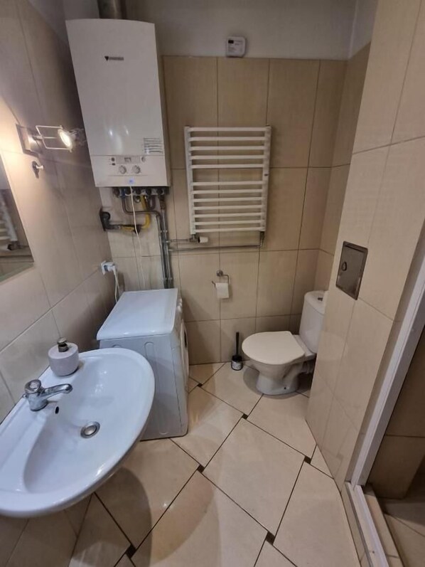 A small, compact bathroom with a sink, toilet, and a radiator. - Fantastic Inn Kraków - KR6 (Kraków)