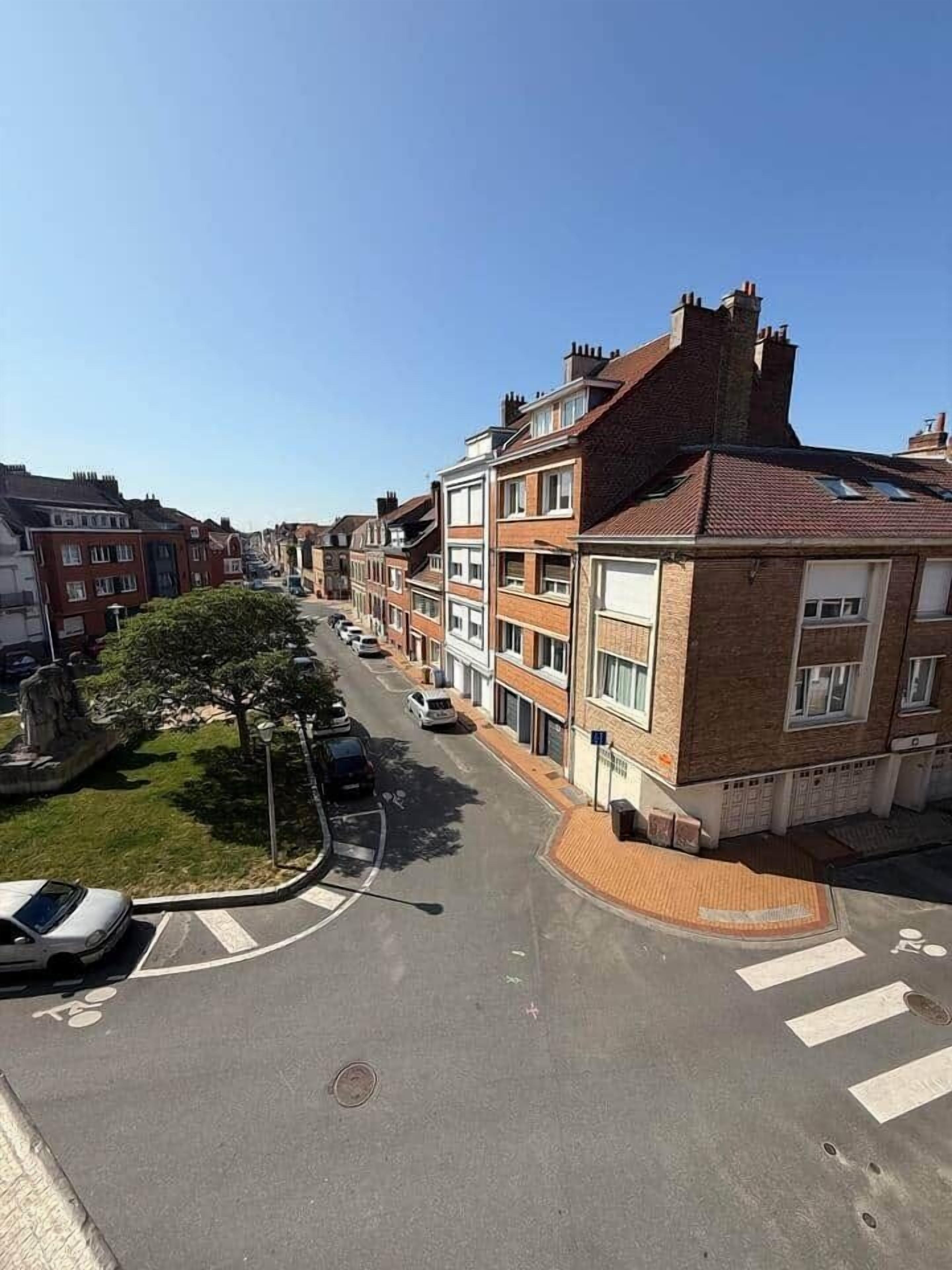 A residential street with terraced houses, a pedestrian crossing, and a car parked on the side.