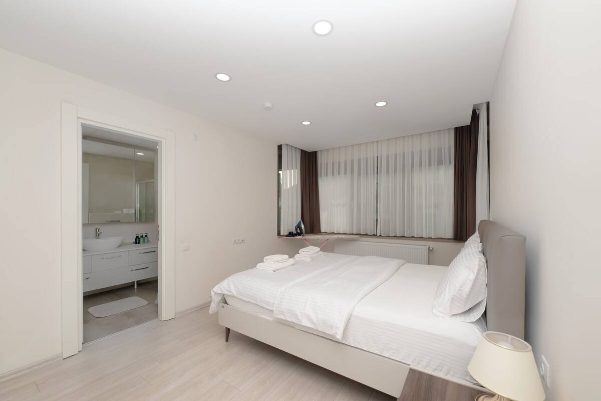 Une chambre à coucher moderne avec un lit, une table de chevet et un miroir au-dessus du lit.