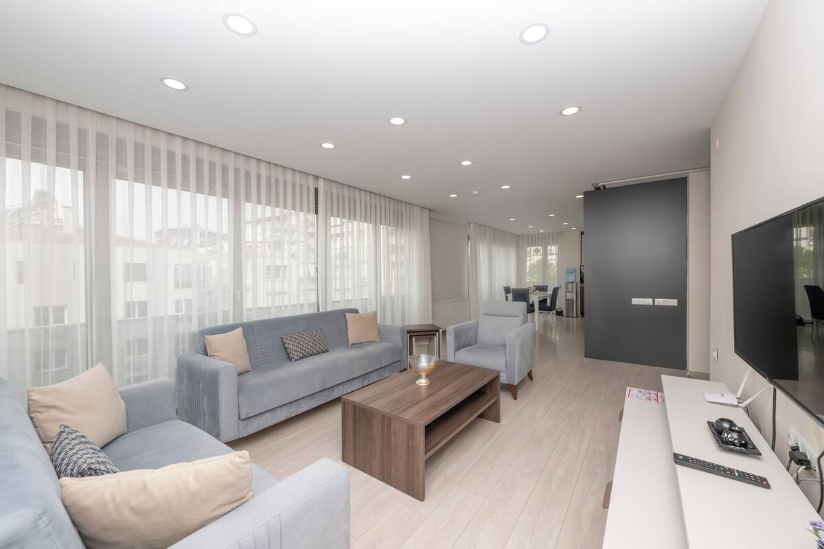 Un salon moderne avec un canapé, une table basse et un téléviseur à écran plat.