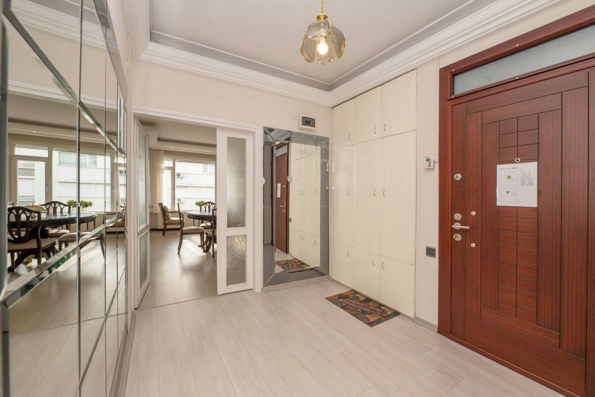 Un hall d’hôtel avec une porte en bois, une cloison en verre et un espace repas comprenant des chaises et une table.