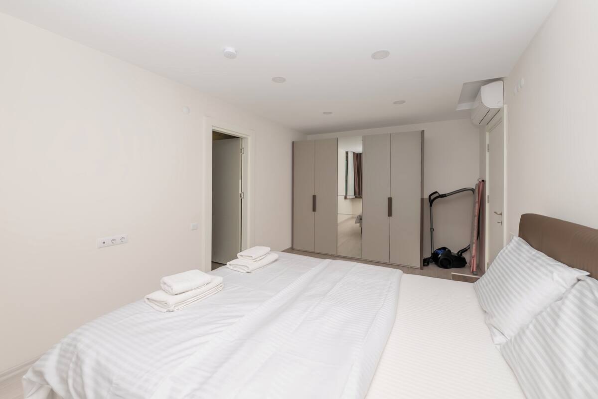 Une chambre d’hôtel avec un grand lit, une armoire, un miroir et un appareil de climatisation fixé au plafond.
