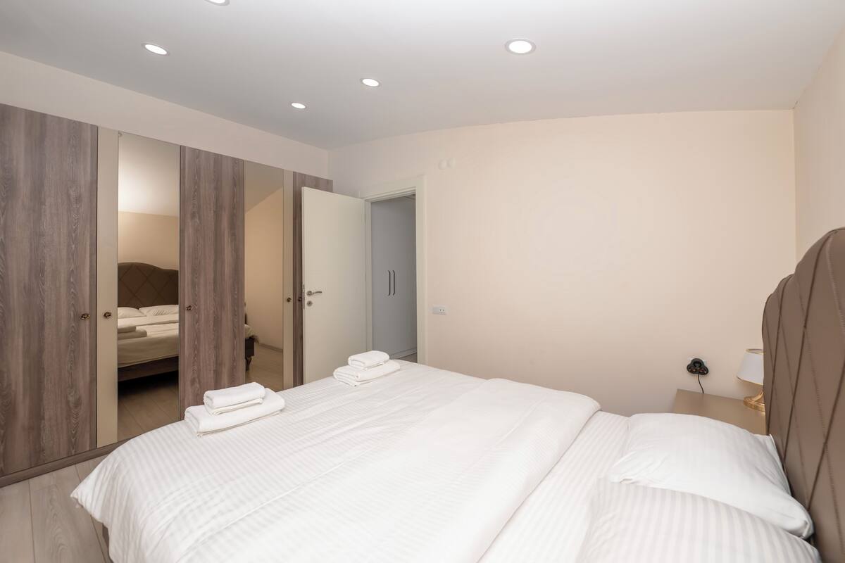 Une chambre moderne avec un grand lit, une armoire et une table de chevet avec une lampe.