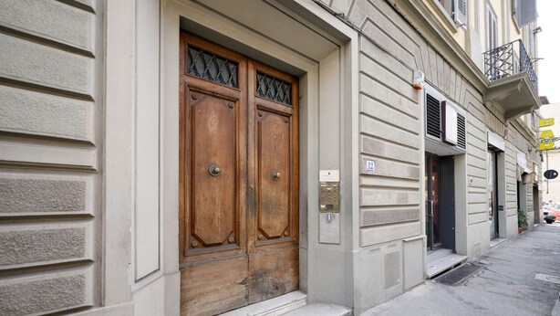 Un edificio con una puerta doble de madera y un pequeño escalón que lleva a la entrada.