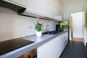 A modern kitchen with white cabinets, a stainless steel refrigerator, a built-in oven, and a black coffee maker. - Santa Maria Novella Deluxe Apartment (firenze)