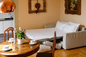 A compact room with a bed, a dining table with chairs, and a small kitchen area. - Santa Maria Novella Deluxe Apartment (firenze)