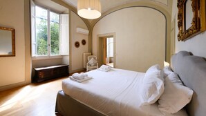 Un dormitorio con una cama grande, una ventana, un radiador y un espejo en la pared.