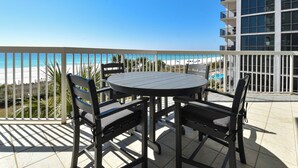 A balcony with a round table and four chairs, overlooking a beach and a pool. - Beachfront 4BR Silver Beach Towers West 306 (Destin)