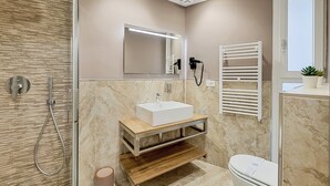 Une salle de bain moderne équipée d’une douche, d’un lavabo, de toilettes, d’un miroir et d’un porte-serviettes.