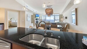 Una cocina moderna con encimera de granito negro, pileta de acero inoxidable e iluminación colgante.