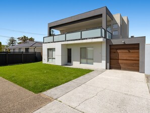 A modern two-story house with a flat roof, a balcony, and a garage. - Baravi Breeze Retreat (Safety Beach)