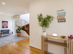 A living room with a sofa, a potted plant, a staircase, and a wall with motivational signs. - Baravi Breeze Retreat (Safety Beach)