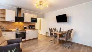 Een moderne keuken met een eethoek, een flatscreen televisie aan de muur en een houten vloer.