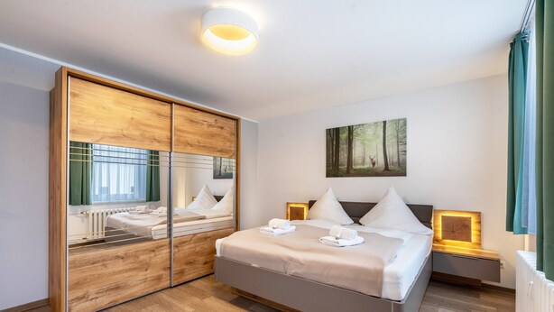 Een moderne hotelkamer met een groot bed, een spiegel, een schilderij en een nachtkastje.