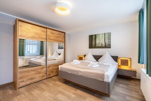 Une chambre d’hôtel moderne avec un grand lit, un miroir, un tableau et une table de chevet.
