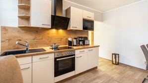 Een moderne keuken met witte kastjes, een houten aanrecht, een inbouwoven, een magnetron en een koffiezetapparaat.