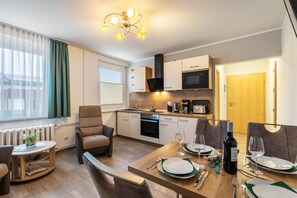 Una cocina moderna con comedor, sofá y mesa dispuesta para dos.