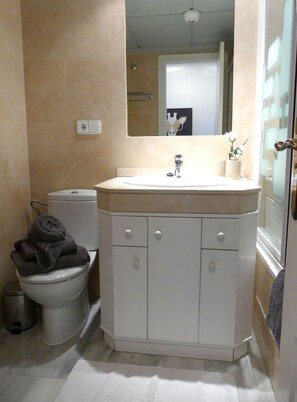 A bathroom with a toilet, sink, mirror, and a towel rack. - Apartment 'Tesoro Del Mar' with Sea View, Wi-Fi, and Air Conditioning (Torrox Costa)