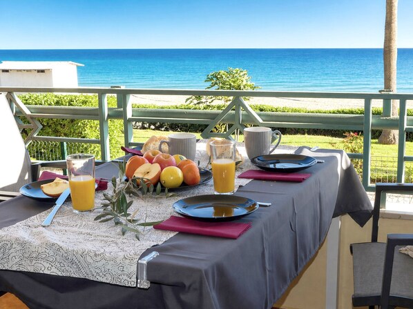 A table set with breakfast items, a glass of orange juice, and a view of the ocean. - Apartment 'Tesoro Del Mar' with Sea View, Wi-Fi, and Air Conditioning (Torrox Costa)