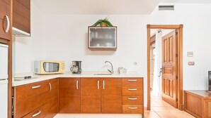 A kitchen with wooden cabinets, a microwave, a coffee maker, and a sink.