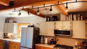 A kitchen with wooden cabinets, a stainless steel refrigerator, a microwave, a stove, and hanging lights. - Cozy 2+ bedroom house in beautiful Springfield (Springfield)