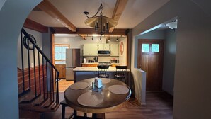 A dining area with a round table, chairs, and a chandelier. A staircase is visible to the left, and a kitchen is in the background. - Cozy 2+ bedroom house in beautiful Springfield (Springfield)