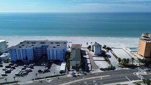 Een hotel aan de kust met een parkeerplaats, een strand en uitzicht op de oceaan.
