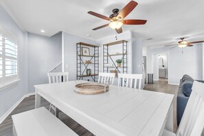 A spacious dining area with a white table and benches, a ceiling fan, and a view into the kitchen. - Beach Access - Community Pool - 3 Story Townhome - El Mar Unit D (Indian Shores)