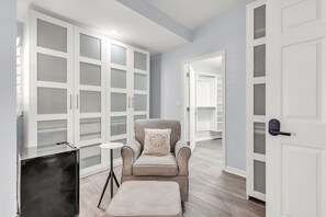 A modern room with a grey armchair, a small side table, and a large closet with glass doors. - Beach Access - Community Pool - 3 Story Townhome - El Mar Unit D (Indian Shores)