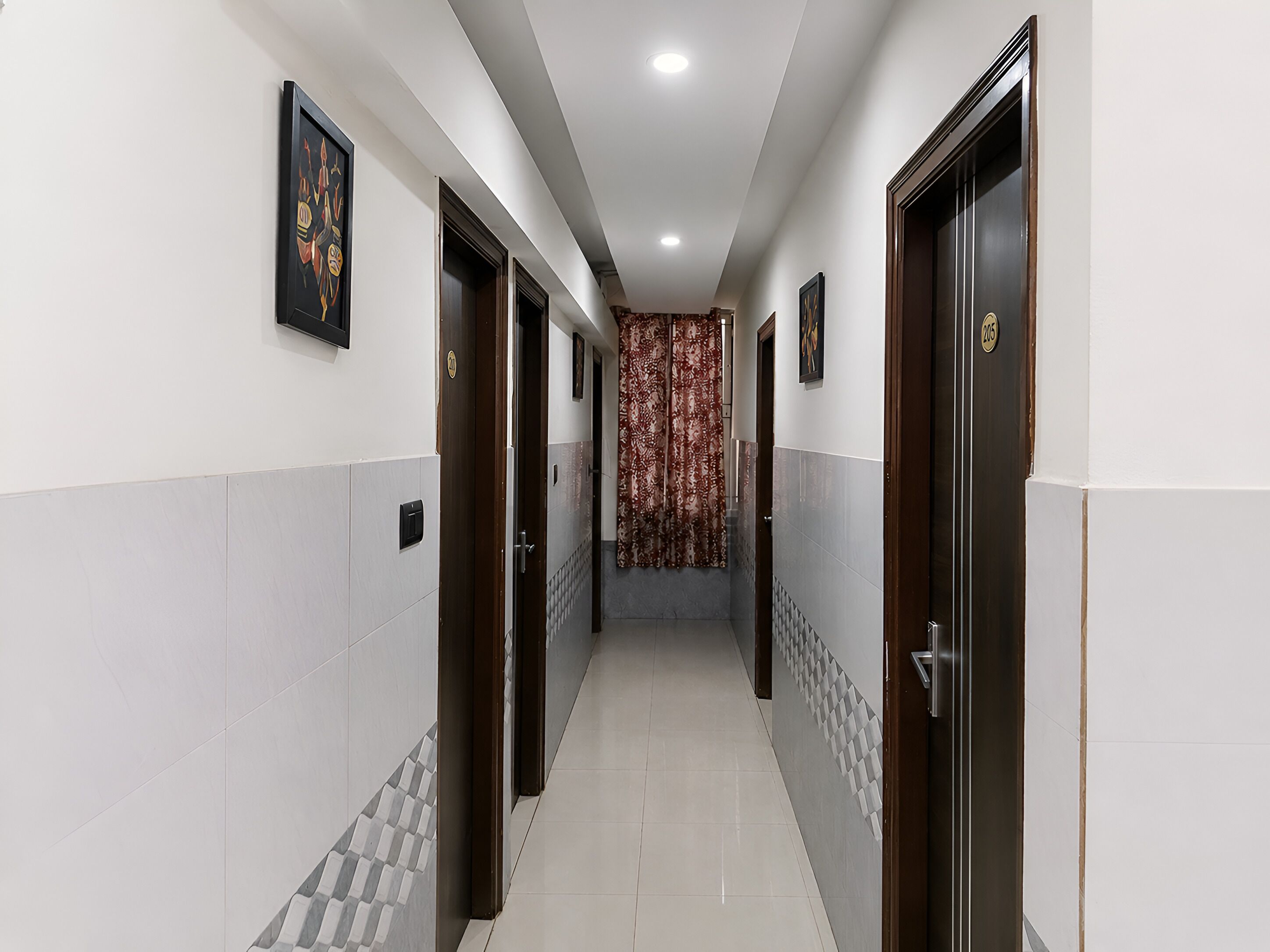 A corridor with doors on both sides, a patterned curtain at the end, and a tiled floor.