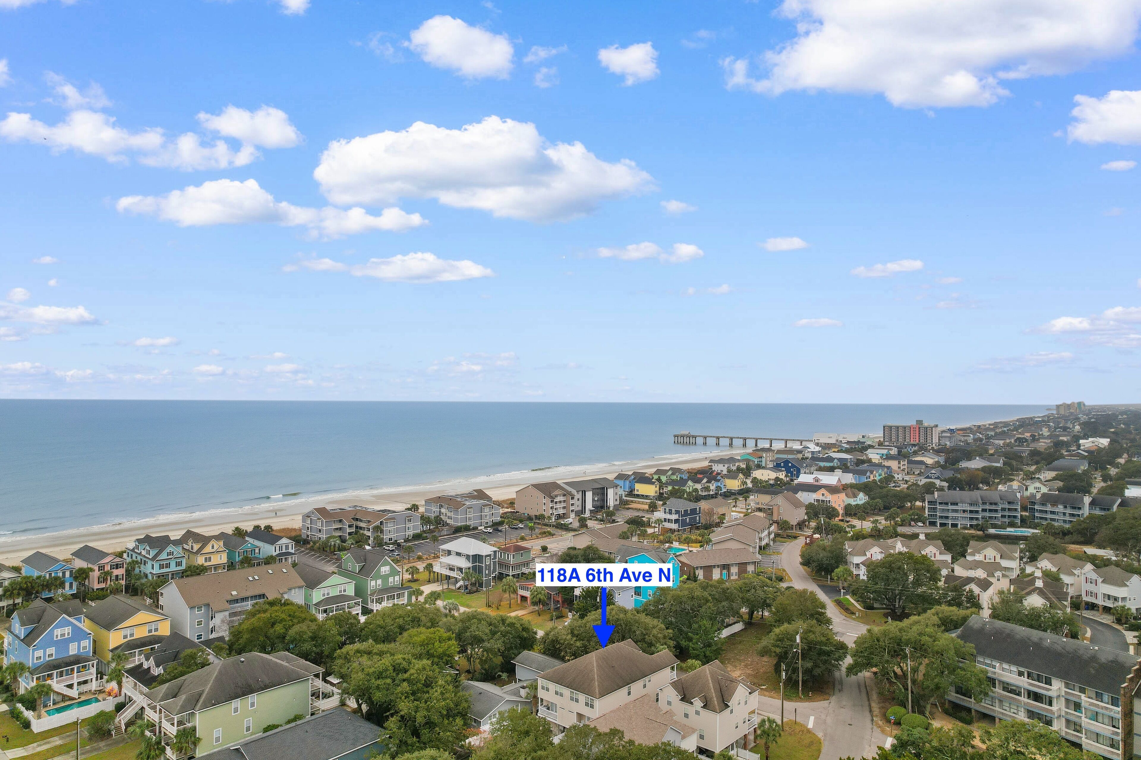 A coastal residential area with houses, a beach, and a pier.