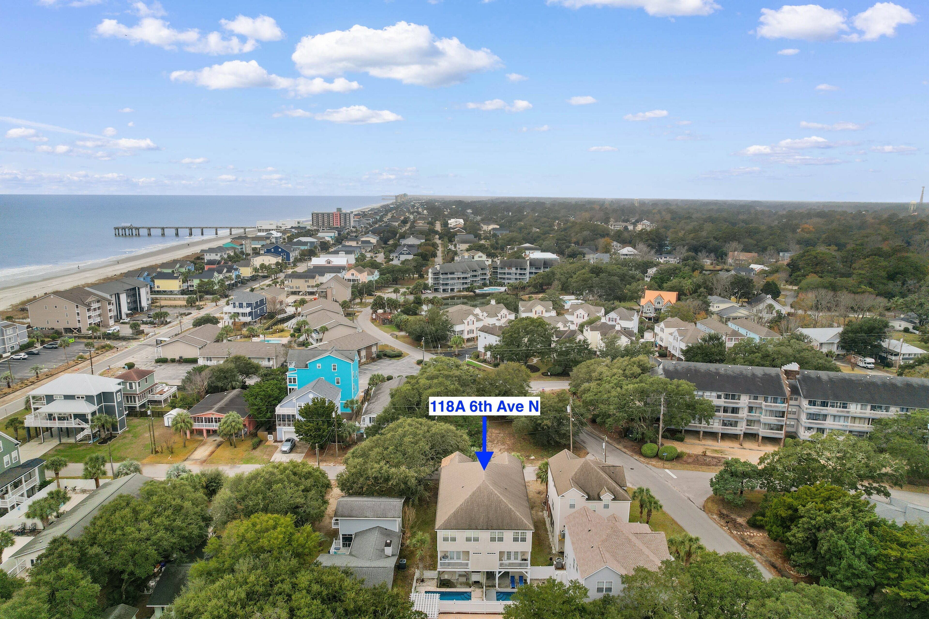 An aerial view of a residential area with houses, a beach, and a pier.