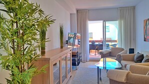 En moderne stue med en sofa, fjernsyn, et træskab og en stor plante.