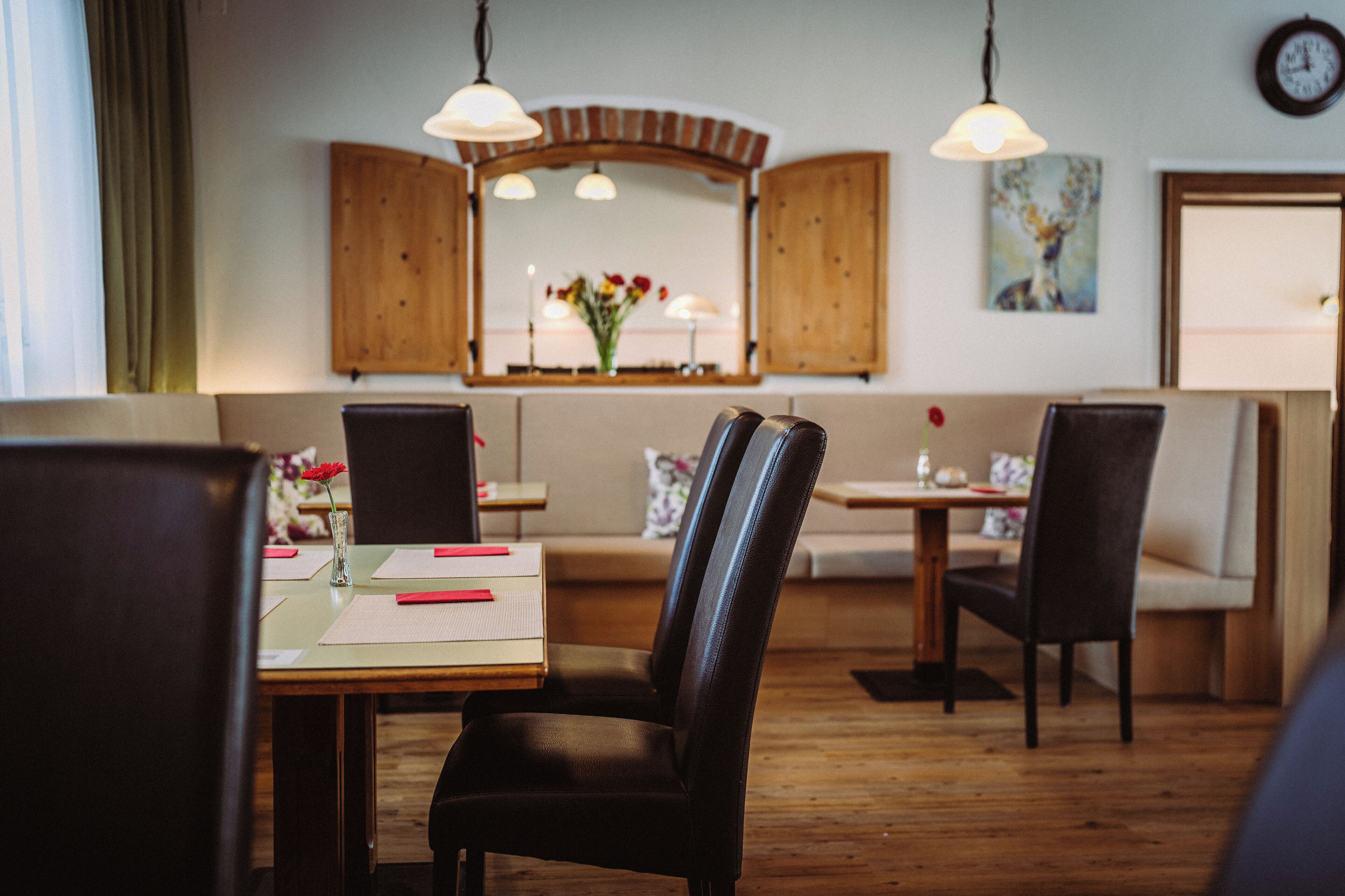 Un coin repas avec des meubles en bois, un miroir et une horloge au mur.