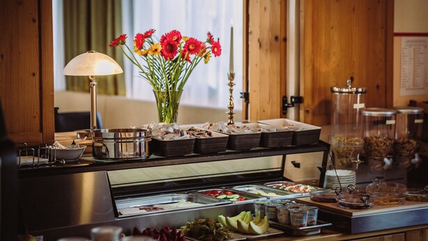 Ein reichhaltiges Buffet mit verschiedenen Speisen, einer Blumenvase und einer Lampe.