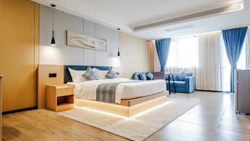 A modern bedroom with a large bed, bedside tables, a desk, and a chair.