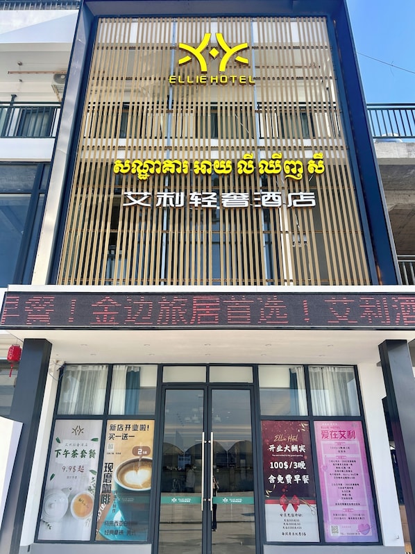 A hotel with a prominent yellow logo and signage in multiple languages. - Ellie Hotel (Phnom Penh)