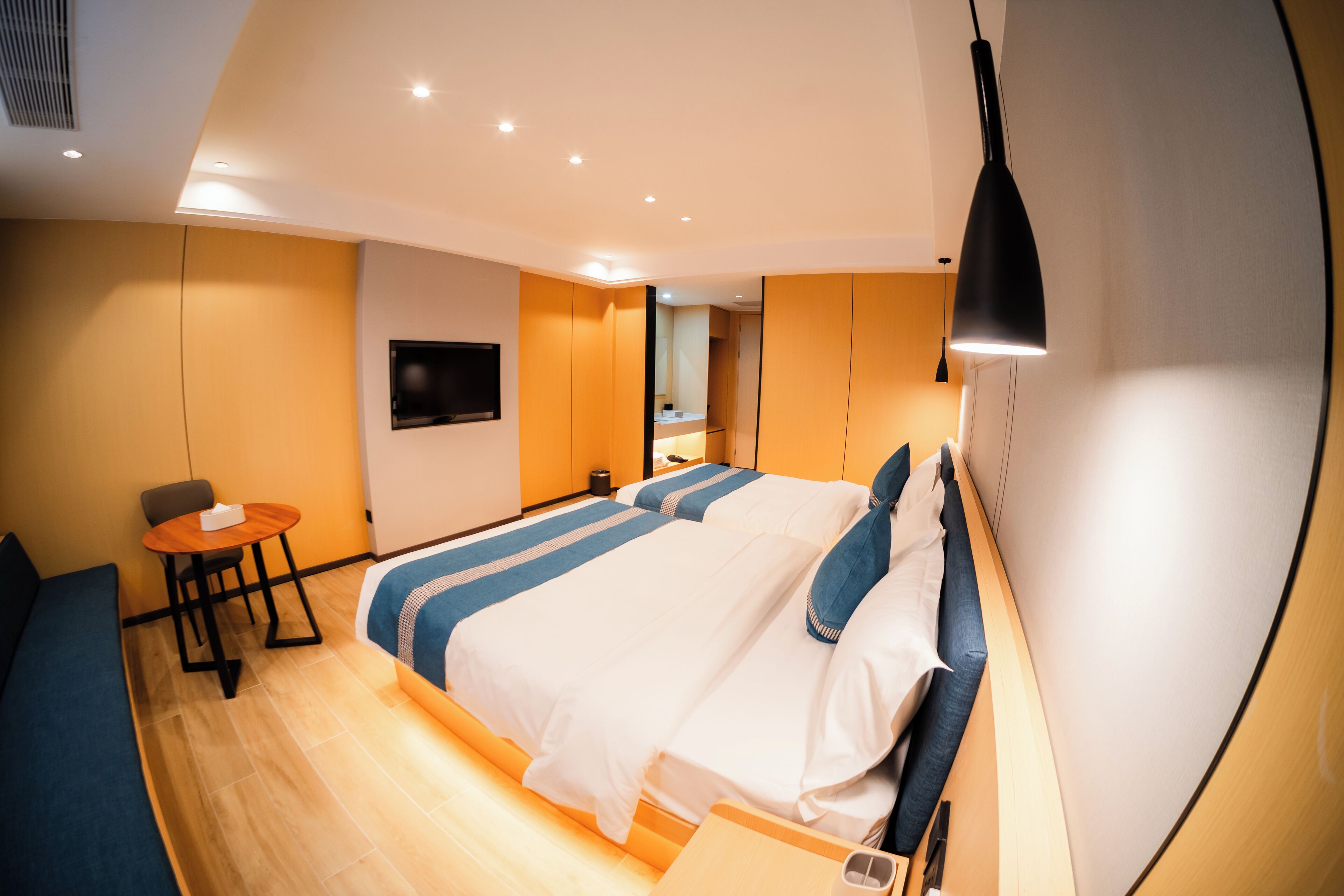 A modern hotel room with a large bed, a desk, and a TV mounted on the wall.