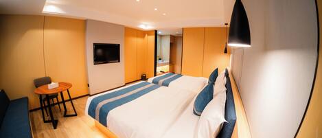 A modern hotel room with a large bed, a desk, and a TV mounted on the wall.