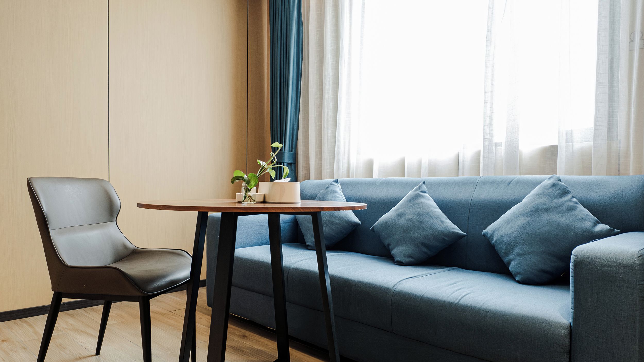 A modern living room with a grey sofa, a wooden table, and a chair.