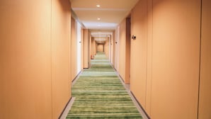 A hotel corridor with a green striped carpet, wooden walls, and a series of doors leading to rooms. - Ellie Hotel (Phnom Penh)