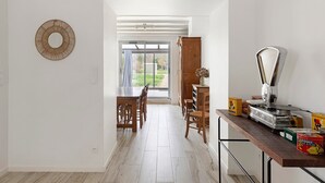 A kitchen with a wooden table, chairs, a coffee machine, and a view through a glass door.