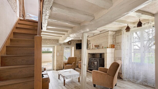 A wooden staircase leading to a living area with a fireplace, two armchairs, and a table.